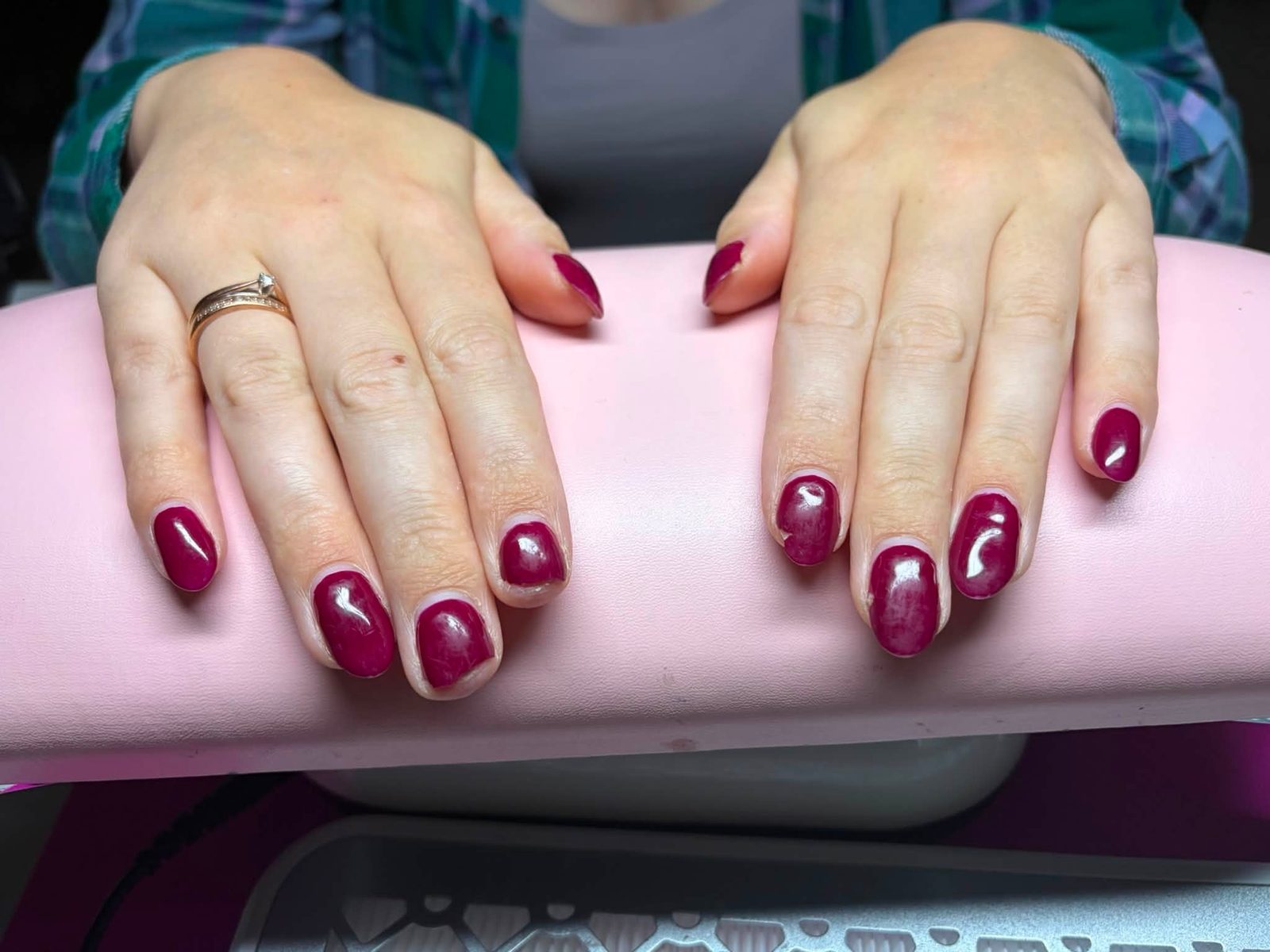 Korte nagels in bessenrood op de roze handsteun