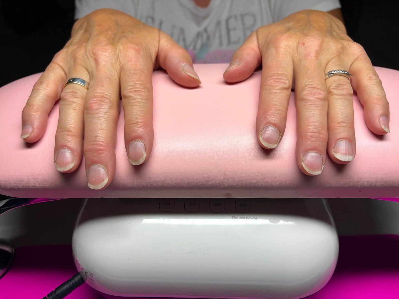 Nagels in doorschijnend nude op de roze handsteun