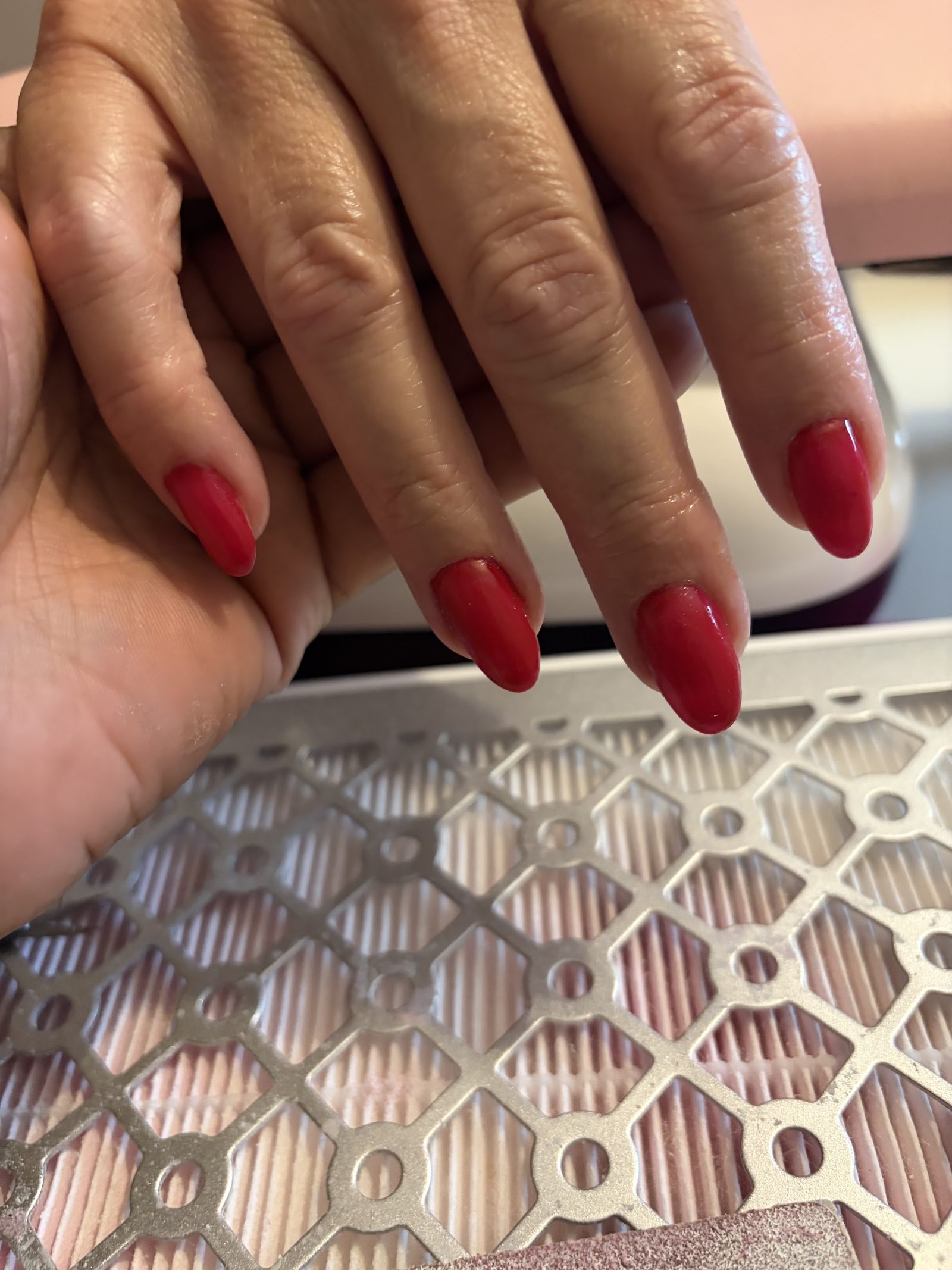 Rode amandelvormige nagels boven de afzuiging van de werktafel
