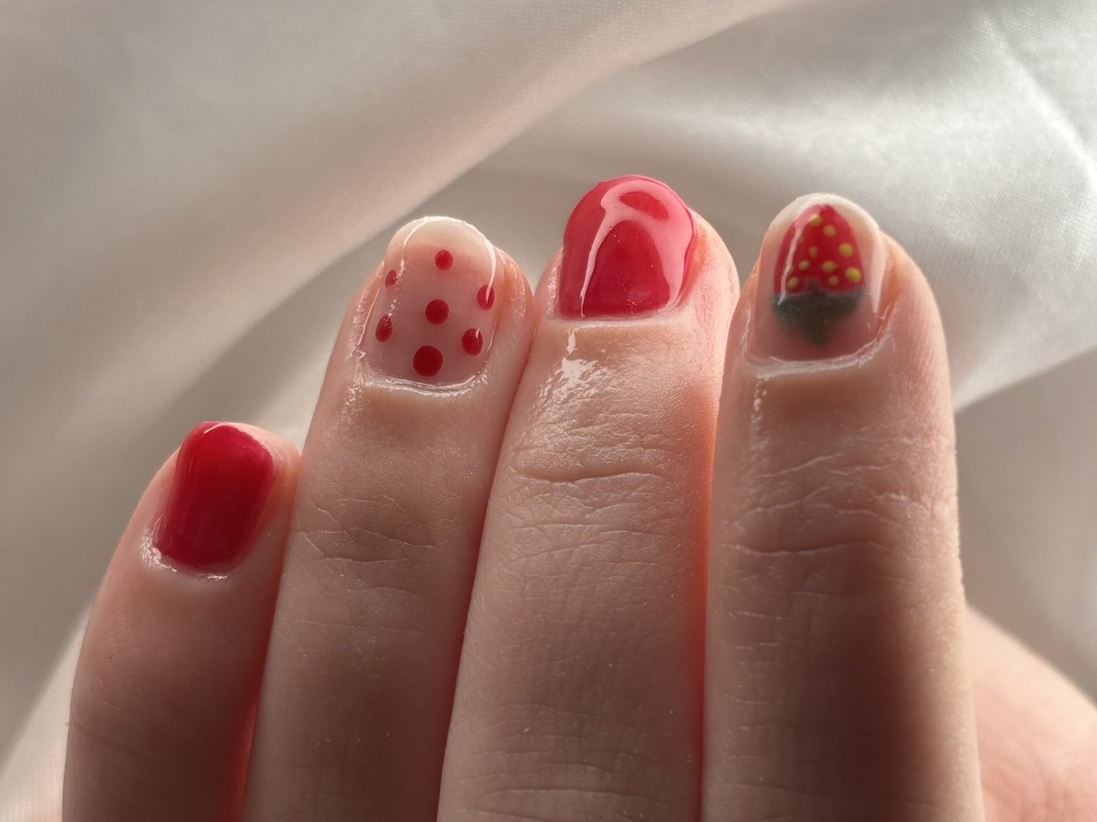Rode nail art met witte stippen en een aardbei