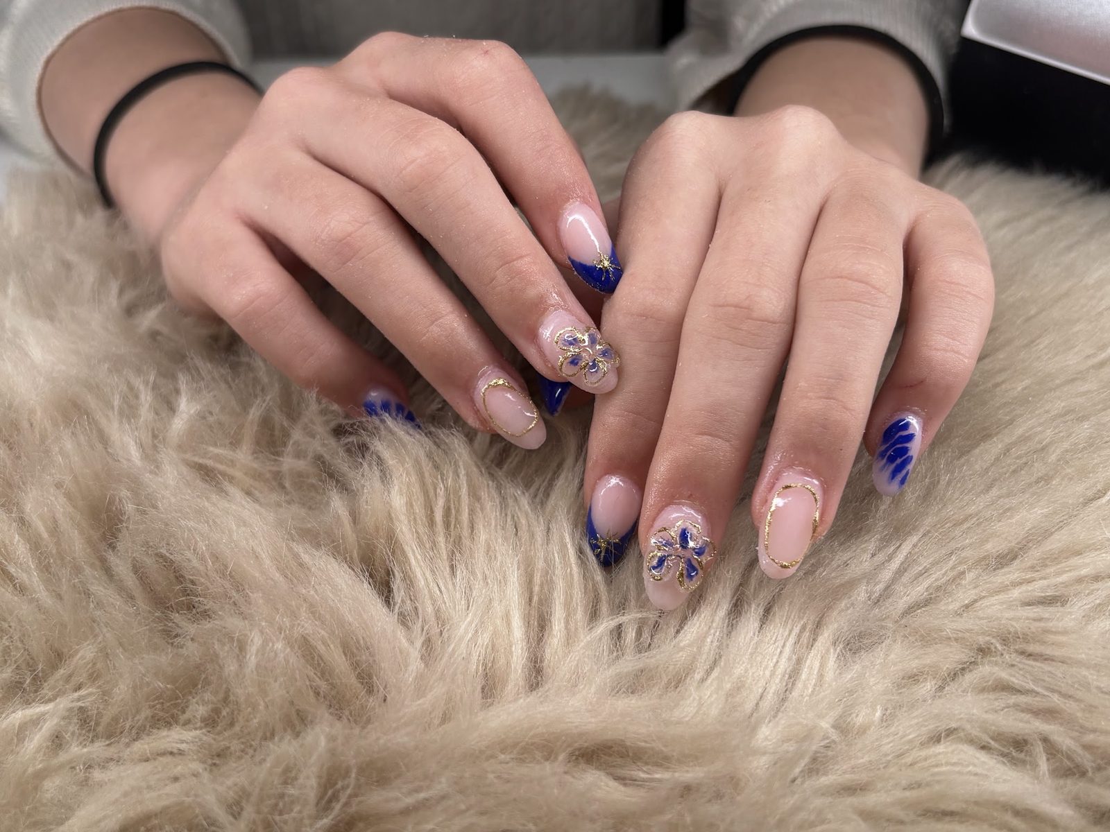 Nude nagels met blauwe en paarse bloemetjes op een beige vachtje